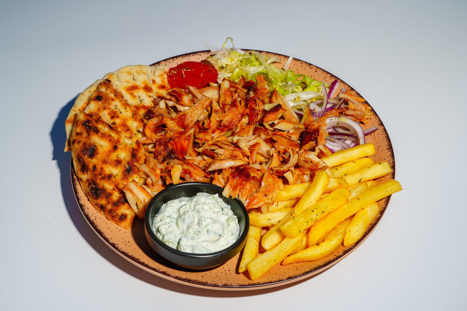 Chicken gyros plate in Malta with fresh pita, tzatziki, fries, salad and red onion at Kreta Paceville